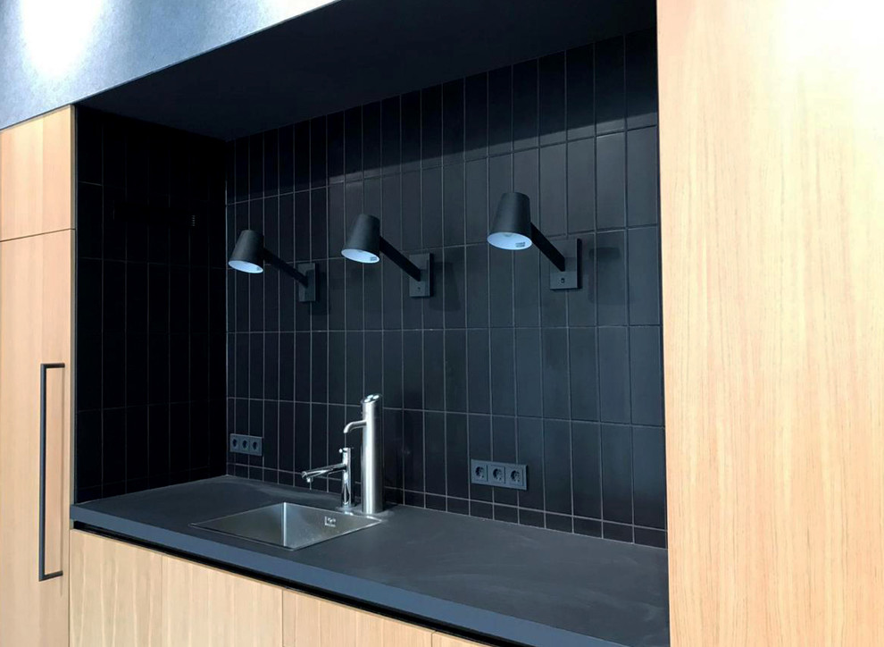 Offene, Einzeilige Moderne Küche ohne Insel mit Einbauwaschbecken, flächenbündigen Schrankfronten, hellen Holzschränken, Laminat-Arbeitsplatte, Küchenrückwand in Schwarz, Rückwand aus Porzellanfliesen und grauer Arbeitsplatte in Berlin