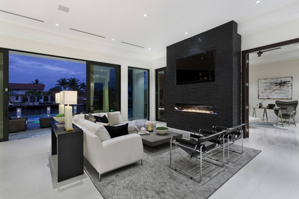 Inspiration for a contemporary open concept living room in Miami with white walls, a ribbon fireplace, a brick fireplace surround, a wall-mounted tv and grey floor.