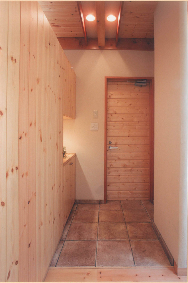 他の地域にある小さな北欧スタイルのおしゃれな玄関 (ベージュの壁、テラコッタタイルの床、淡色木目調のドア、ベージュの床) の写真