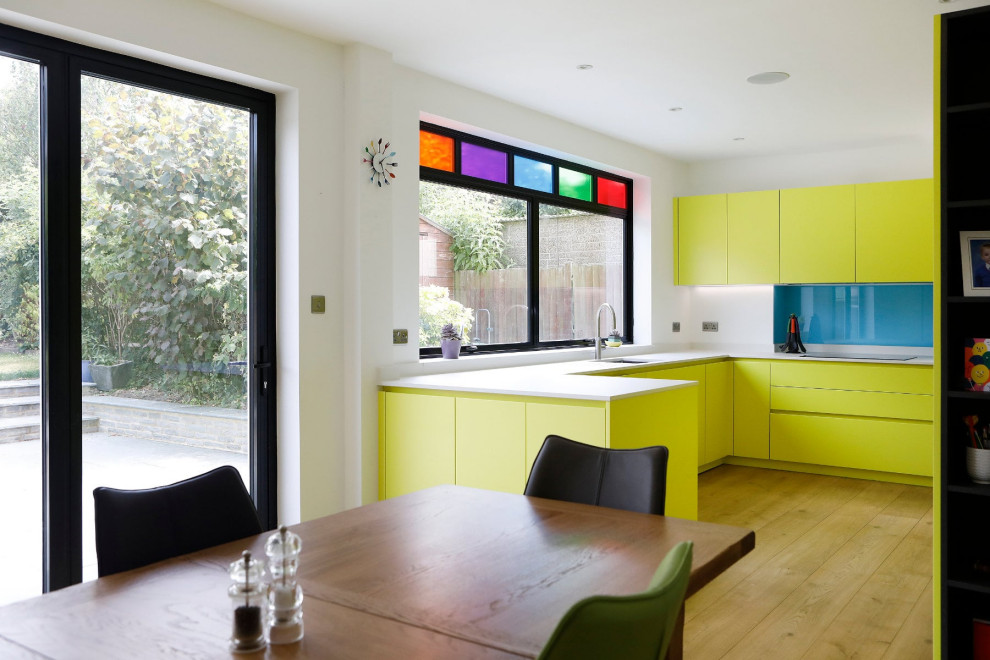 Design ideas for a small contemporary l-shaped eat-in kitchen in London with an undermount sink, flat-panel cabinets, yellow cabinets, quartzite benchtops, white splashback, engineered quartz splashback, black appliances, light hardwood floors, beige floor and white benchtop.