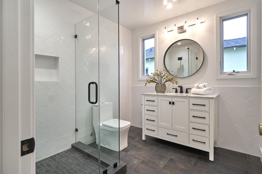 Photo of a mid-sized modern bathroom in Los Angeles with shaker cabinets, white cabinets, a corner shower, a one-piece toilet, multi-coloured tile, ceramic tile, porcelain floors, marble benchtops, grey floor, multi-coloured benchtops, a single vanity and a freestanding vanity.