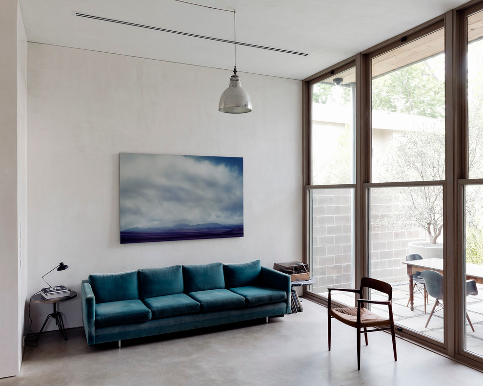 This is an example of a mid-sized contemporary enclosed living room in Other with concrete floors and white walls.