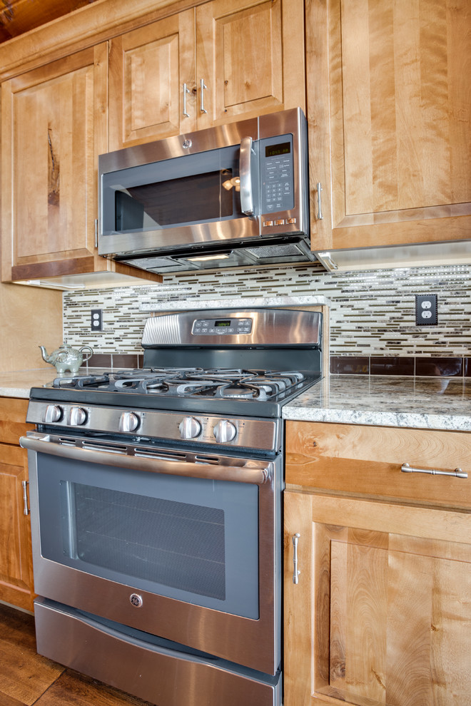 Example of a large mountain style kitchen design in DC Metro with an undermount sink, raised-panel cabinets, granite countertops, glass tile backsplash, stainless steel appliances and an island