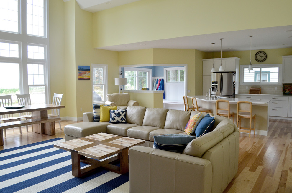 This is an example of a large beach style open concept living room in Detroit with yellow walls and light hardwood floors.
