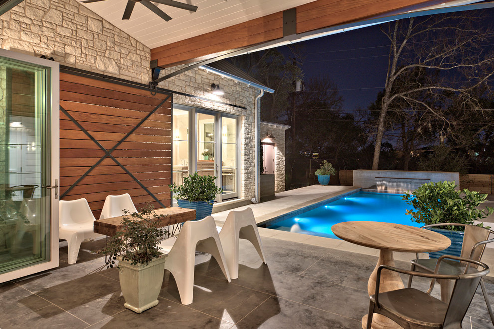 This is an example of a mid-sized country courtyard rectangular lap pool in Austin with a water feature and concrete slab.