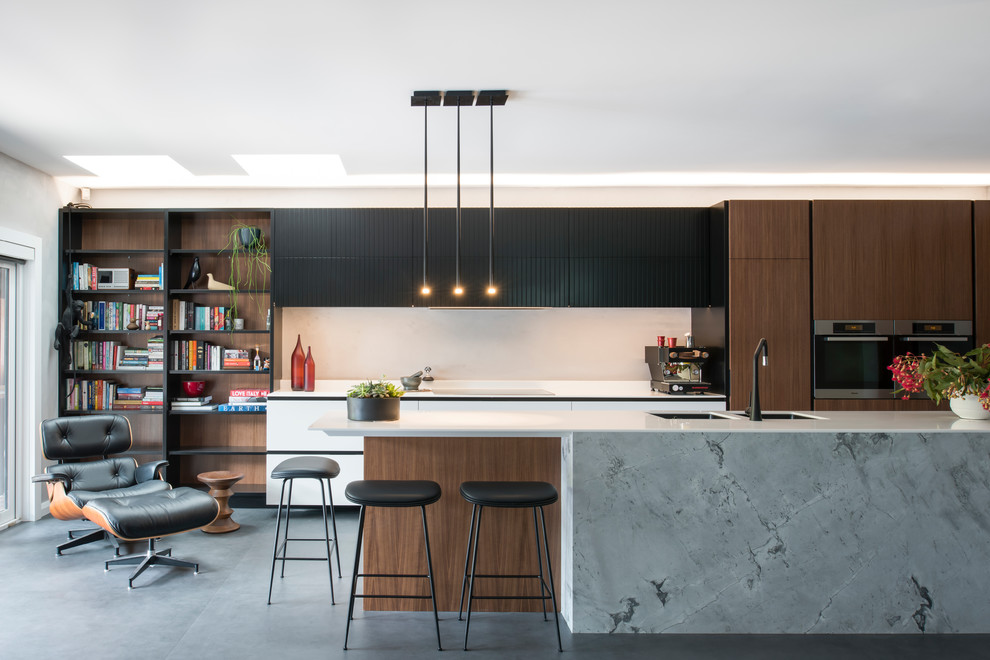 This is an example of a large contemporary l-shaped open plan kitchen in Sydney with a double-bowl sink, flat-panel cabinets, solid surface benchtops, grey splashback, stainless steel appliances, porcelain floors, with island, black floor, white benchtop and dark wood cabinets.