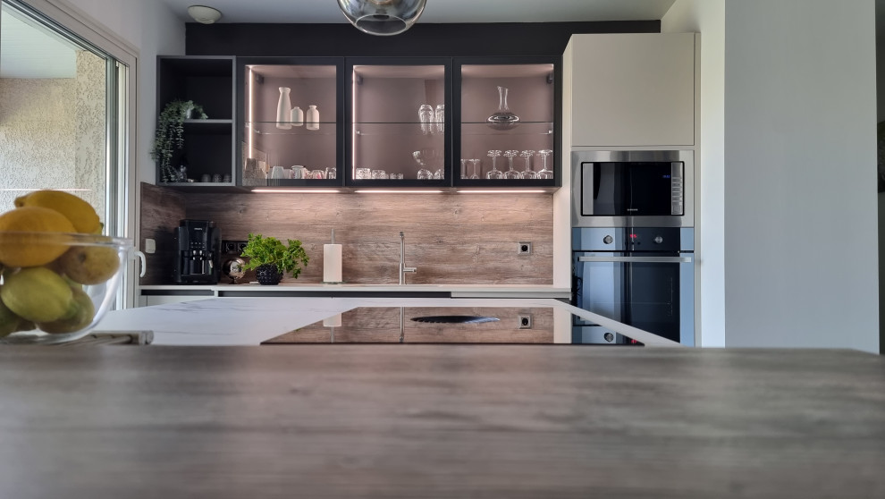 Medium sized contemporary single-wall kitchen in Toulouse with an integrated sink, glass-front cabinets, beige cabinets, granite worktops, brown splashback, wood splashback, black appliances, an island and white worktops.
