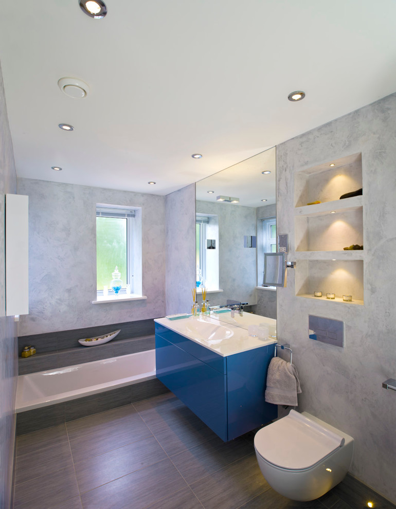 Design ideas for a large contemporary kids bathroom in London with blue cabinets, a drop-in tub and a wall-mount toilet.