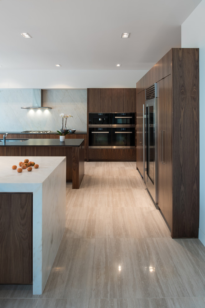 Inspiration for a contemporary l-shaped open plan kitchen in Houston with an undermount sink, flat-panel cabinets, dark wood cabinets, marble benchtops, grey splashback, black appliances, multiple islands and beige floor.