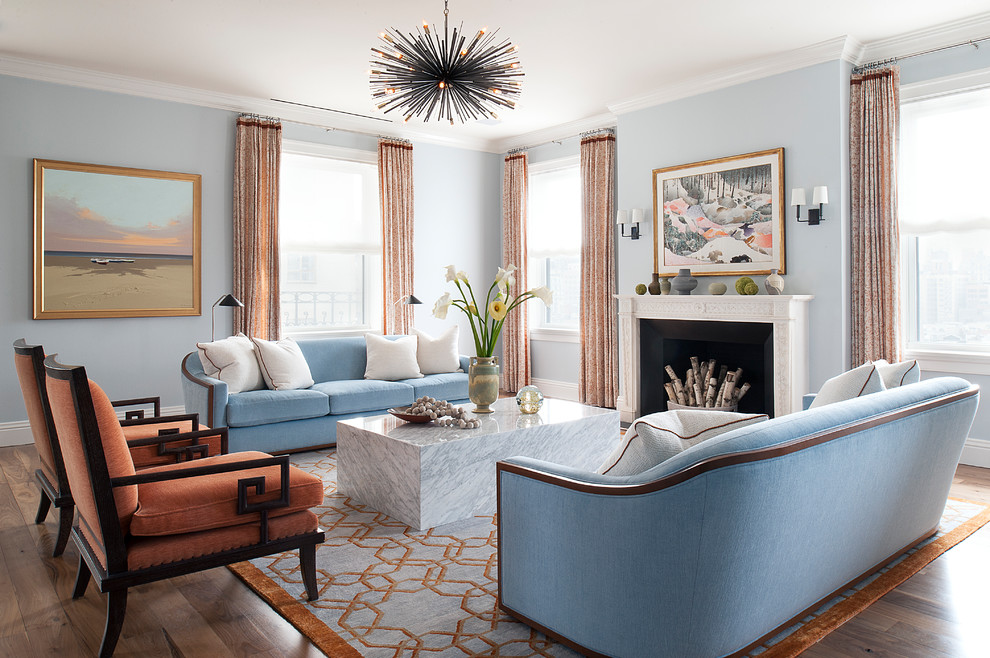 Photo of a transitional living room in New York with blue walls, medium hardwood floors, a standard fireplace and brown floor.