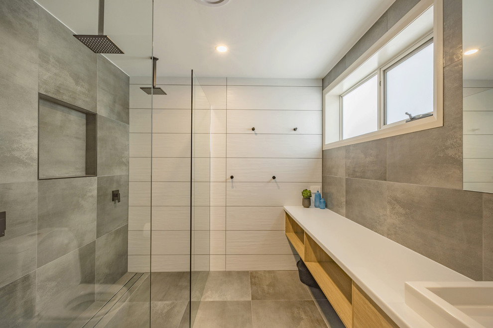 Inspiration for a mid-sized beach style 3/4 bathroom in Other with flat-panel cabinets, beige cabinets, an alcove shower, a one-piece toilet, ceramic tile, white walls, ceramic floors, a drop-in sink, granite benchtops, white floor, a hinged shower door and beige benchtops.
