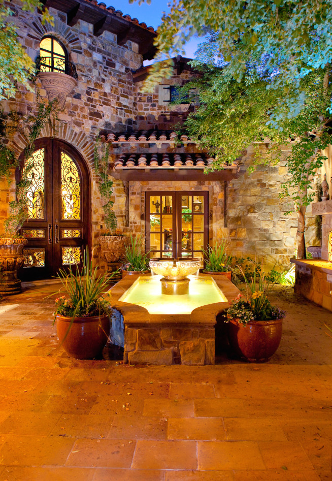 Photo of an expansive country courtyard patio in Phoenix with a water feature, natural stone pavers and no cover.