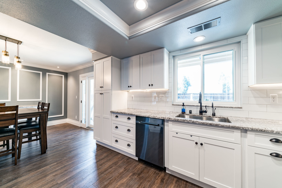 Inspiration for a mid-sized transitional u-shaped dark wood floor and brown floor eat-in kitchen remodel with an undermount sink, shaker cabinets, white cabinets, granite countertops, white backsplash, subway tile backsplash, stainless steel appliances and an island