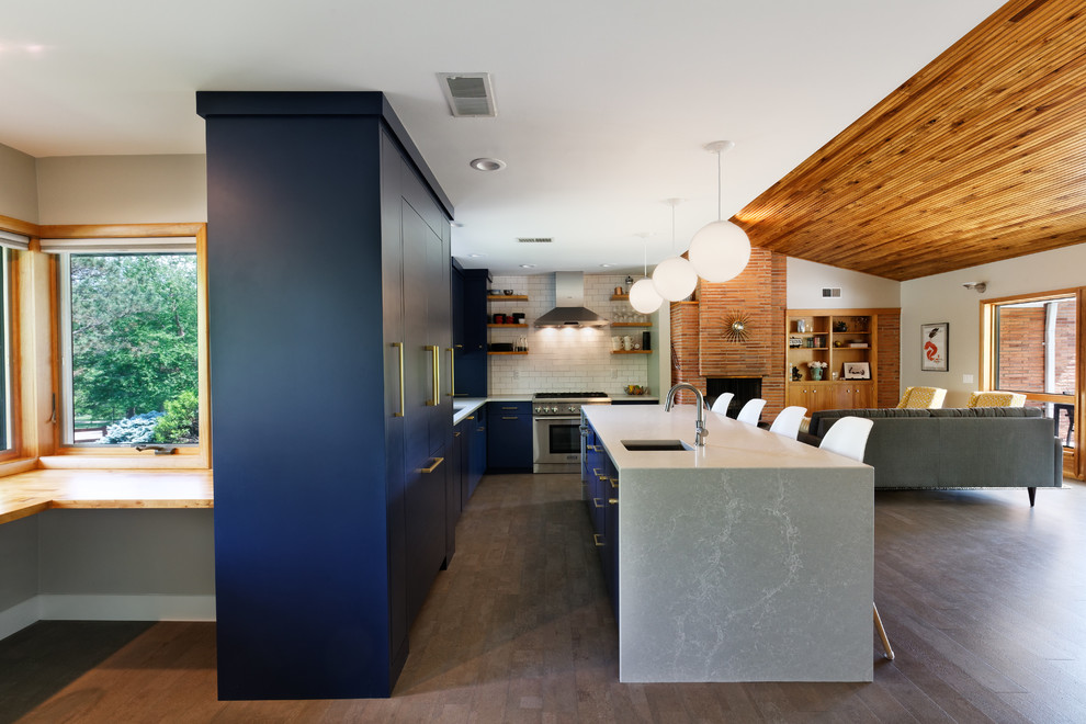 Photo of a midcentury l-shaped open plan kitchen in Cincinnati with flat-panel cabinets, blue cabinets, cork floors, with island, an undermount sink, white splashback, quartzite benchtops, ceramic splashback, panelled appliances, white benchtop and grey floor.