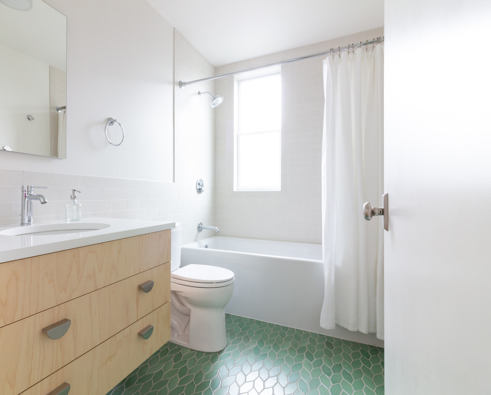 Inspiration for a scandinavian 3/4 bathroom in Boston with flat-panel cabinets, light wood cabinets, an alcove tub, a shower/bathtub combo, a two-piece toilet, porcelain tile, white walls, ceramic floors, an undermount sink, engineered quartz benchtops, green floor, a shower curtain, white benchtops and white tile.