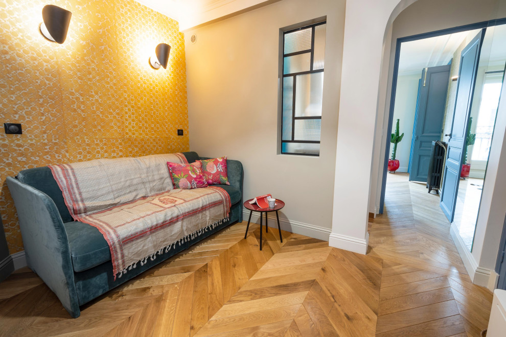 Kleines Stilmix Lesezimmer mit gelber Wandfarbe, hellem Holzboden, Einbau-Schreibtisch, beigem Boden und Tapetenwänden in Paris