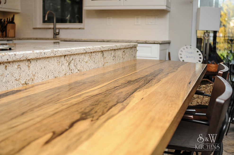 Inspiration for a mid-sized transitional galley porcelain tile eat-in kitchen remodel in Tampa with a farmhouse sink, flat-panel cabinets, white cabinets, wood countertops, white backsplash, subway tile backsplash, stainless steel appliances and a peninsula
