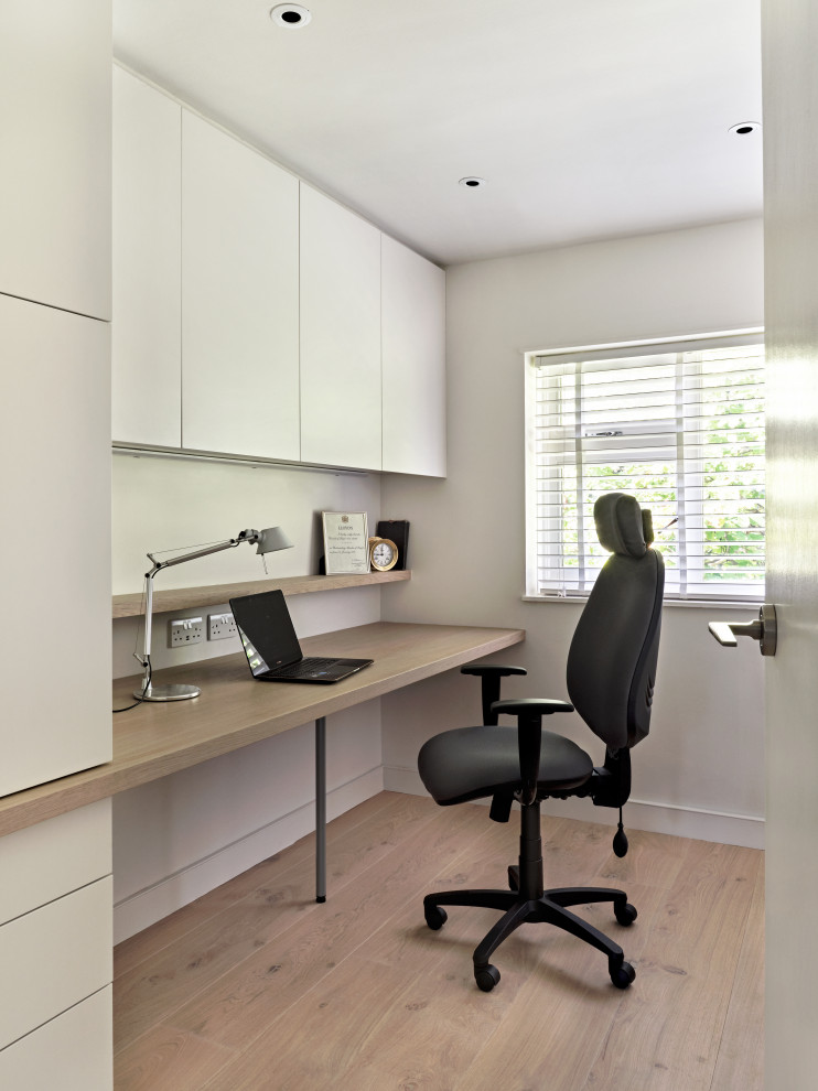 Modelo de despacho actual de tamaño medio con paredes blancas, suelo de madera clara y escritorio empotrado