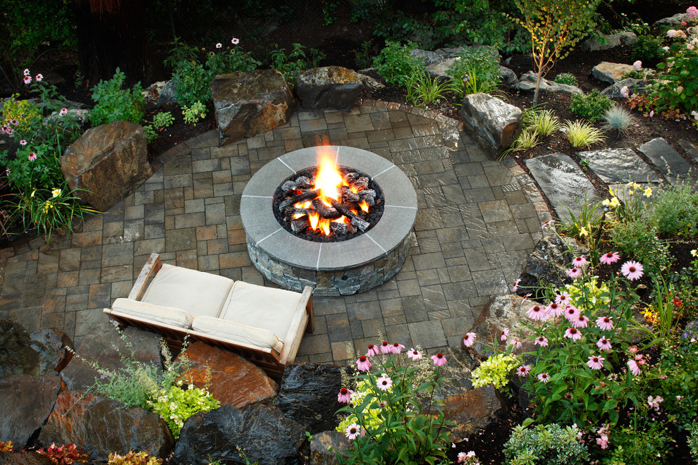 This is an example of a large traditional backyard patio in Seattle with a fire feature, natural stone pavers and no cover.