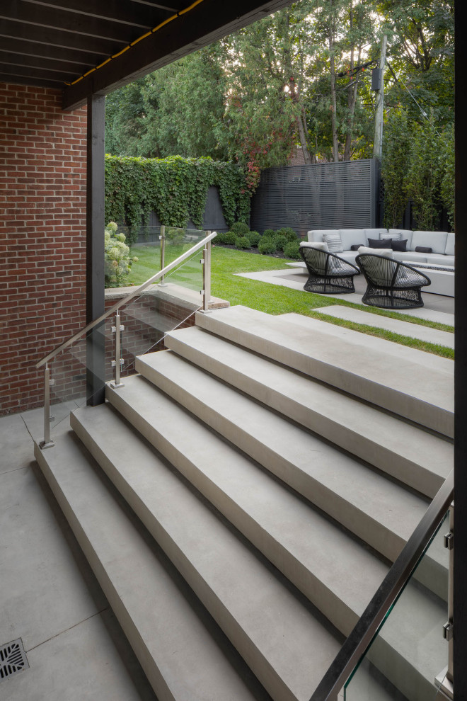 Photo of a mid-sized midcentury backyard patio in Toronto with concrete slab and a roof extension.