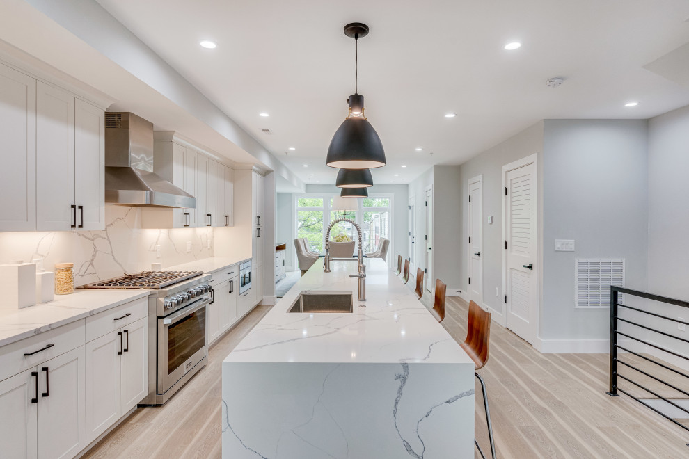 Photo of a mid-sized transitional single-wall eat-in kitchen in DC Metro with an undermount sink, flat-panel cabinets, quartz benchtops, engineered quartz splashback, stainless steel appliances and with island.