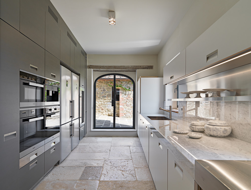 Photo of a contemporary galley kitchen in Milan with an undermount sink, flat-panel cabinets, white cabinets, beige splashback, stainless steel appliances and beige floor.
