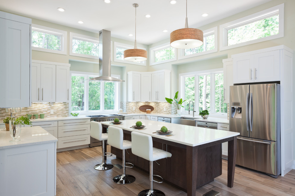 Photo of an expansive transitional u-shaped kitchen in Atlanta with a farmhouse sink, shaker cabinets, white cabinets, quartz benchtops, beige splashback, glass tile splashback, stainless steel appliances, porcelain floors, with island, beige floor and white benchtop.