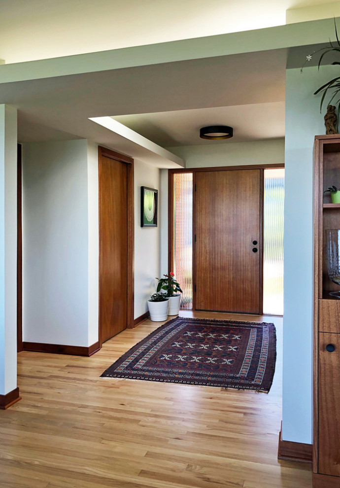 Ejemplo de puerta principal retro de tamaño medio con paredes blancas, suelo de madera clara, puerta simple, puerta de madera en tonos medios, suelo marrón y bandeja