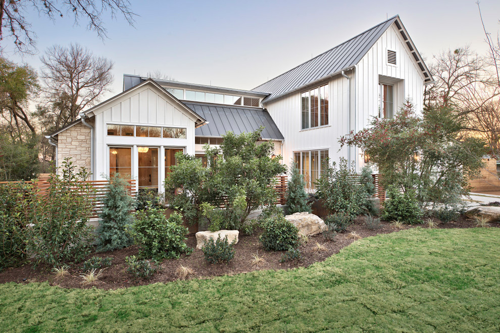 Large transitional two-storey white house exterior in Austin with mixed siding, a gable roof and a metal roof.
