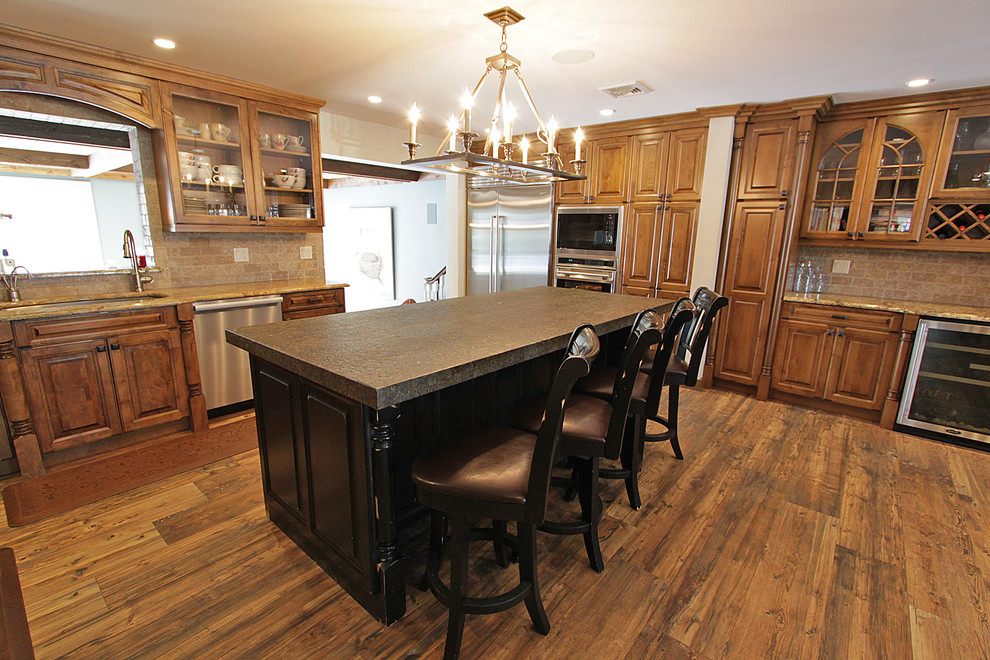 Eat-in kitchen - large rustic u-shaped medium tone wood floor and brown floor eat-in kitchen idea with an undermount sink, raised-panel cabinets, medium tone wood cabinets, granite countertops, beige backsplash, stone tile backsplash, stainless steel appliances and an island