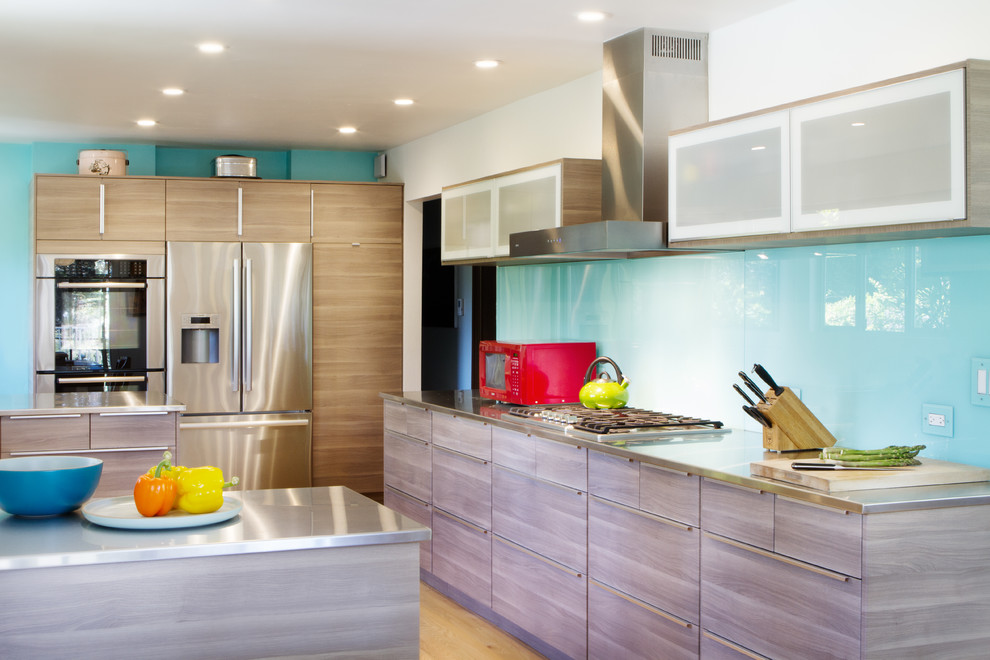 Design ideas for a midcentury u-shaped kitchen in San Francisco with an integrated sink, flat-panel cabinets, light wood cabinets, stainless steel benchtops, blue splashback, glass sheet splashback, stainless steel appliances and light hardwood floors.