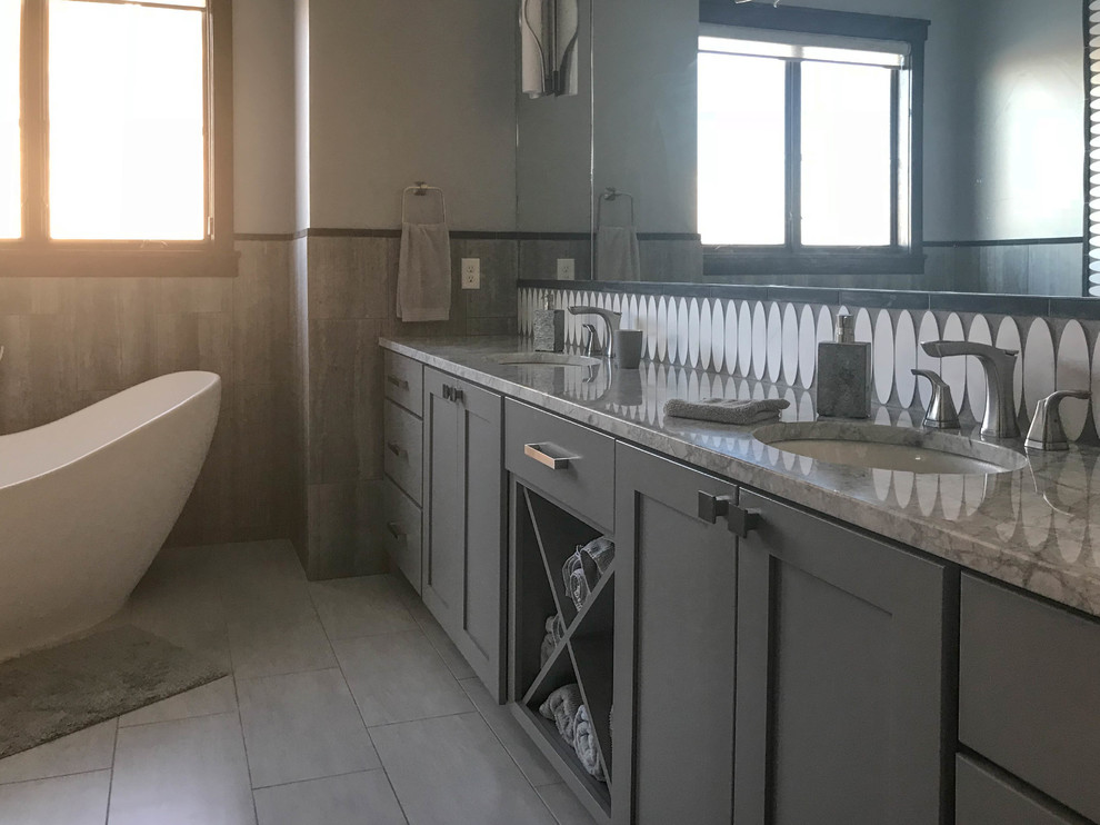 Mid-sized transitional master white tile and porcelain tile porcelain tile freestanding bathtub photo with recessed-panel cabinets, gray cabinets, a two-piece toilet, white walls, an undermount sink and granite countertops