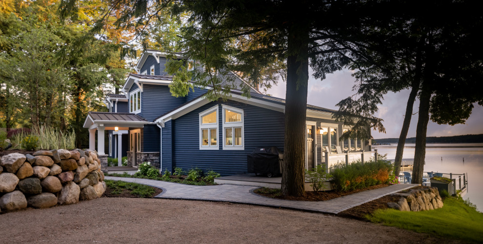 Large traditional blue house exterior in Other with four or more storeys, vinyl siding, a metal roof and a grey roof.