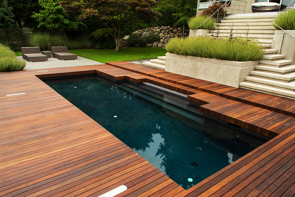 Inspiration for a mid-sized midcentury backyard rectangular lap pool in Vancouver with a water feature and decking.