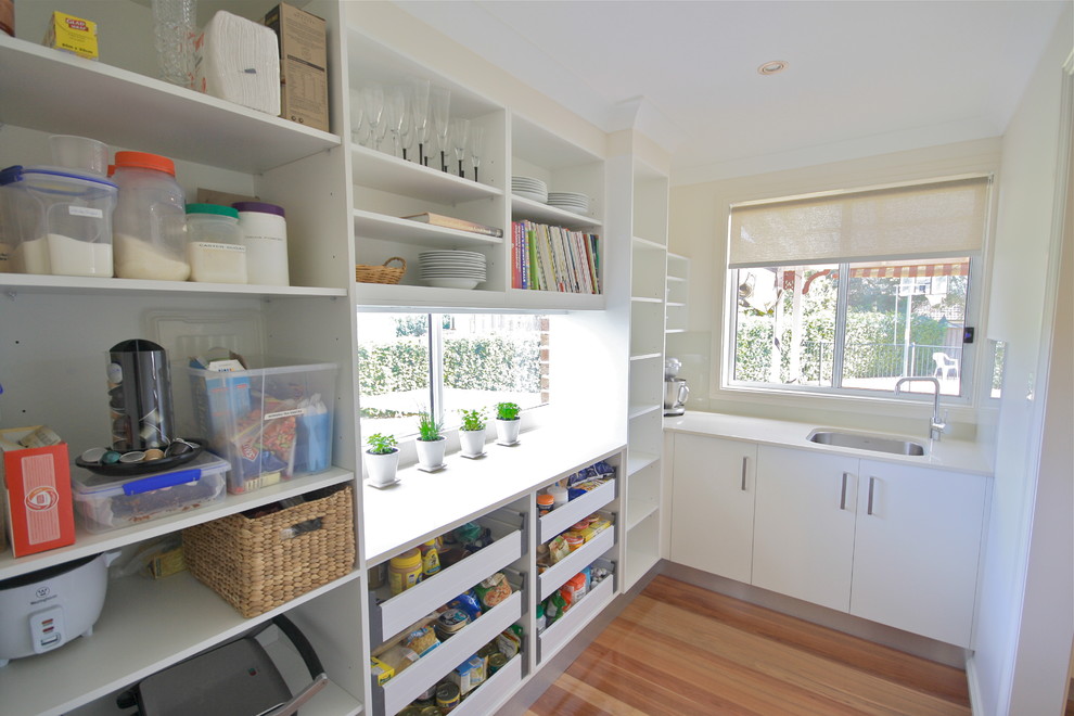 Inspiration for a mid-sized traditional u-shaped kitchen pantry in Sydney with an undermount sink, open cabinets, white cabinets, quartz benchtops, medium hardwood floors, stainless steel appliances and no island.