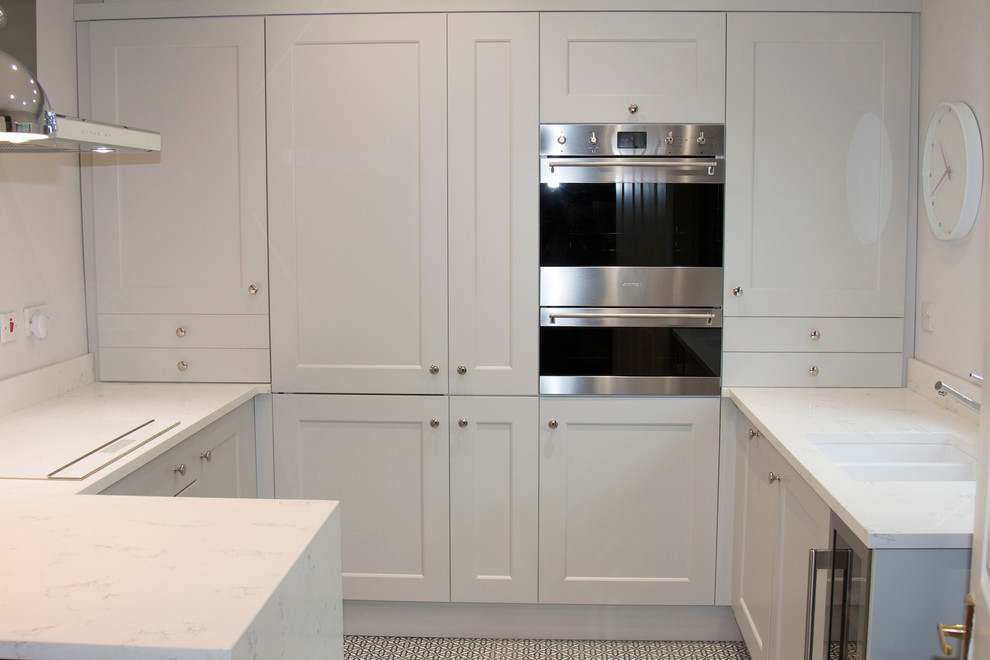 Inspiration for a small traditional u-shaped enclosed kitchen in Belfast with a submerged sink, recessed-panel cabinets, grey cabinets, quartz worktops, white splashback, stone slab splashback, stainless steel appliances, ceramic flooring and a breakfast bar.