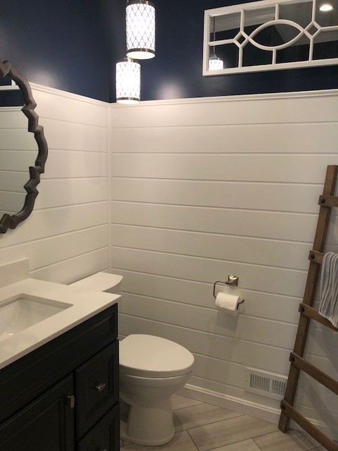 Design ideas for a mid-sized transitional 3/4 bathroom in DC Metro with recessed-panel cabinets, black cabinets, a two-piece toilet, blue walls, porcelain floors, an undermount sink, engineered quartz benchtops, beige floor and white benchtops.
