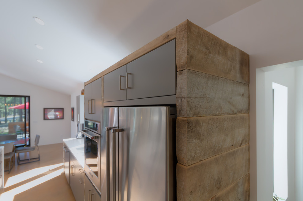 Open concept kitchen - large transitional u-shaped medium tone wood floor and brown floor open concept kitchen idea in Phoenix with an undermount sink, flat-panel cabinets, gray cabinets, solid surface countertops, white backsplash, stainless steel appliances and an island