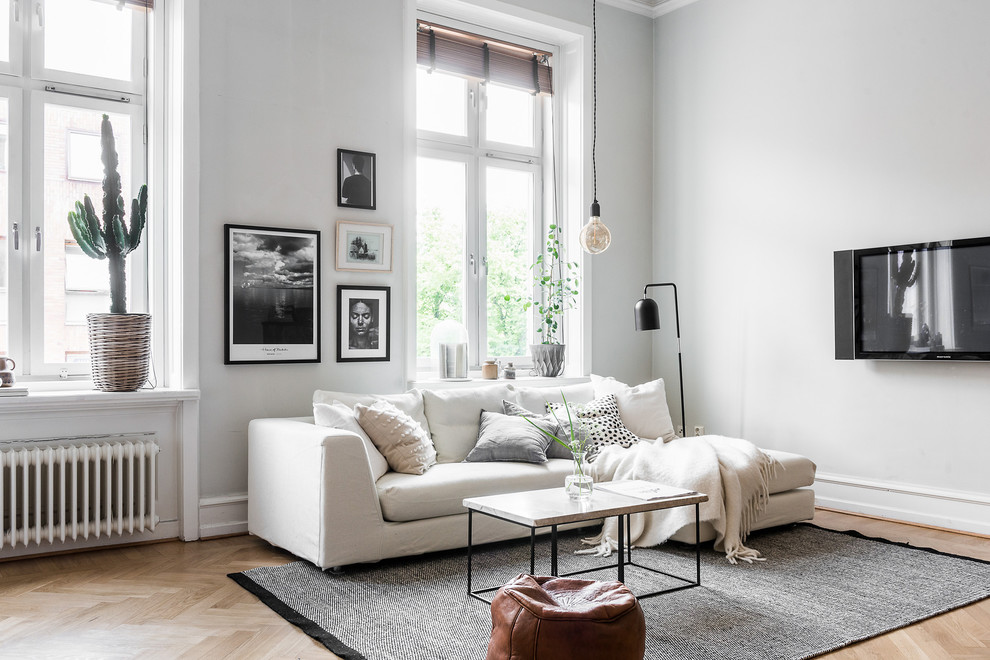 Design ideas for a mid-sized scandinavian formal open concept living room in Gothenburg with grey walls, light hardwood floors and a wall-mounted tv.