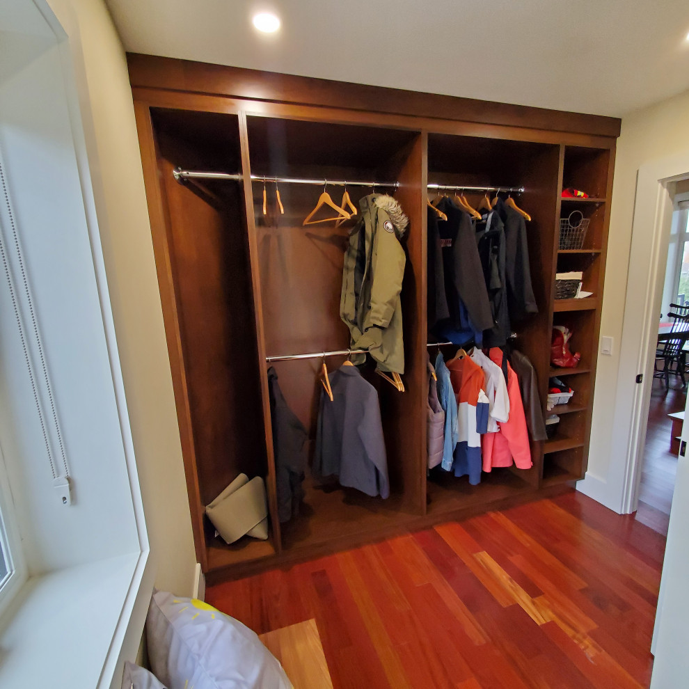 Modelo de armario vestidor unisex minimalista grande con armarios abiertos, puertas de armario de madera oscura, suelo de madera en tonos medios y suelo marrón