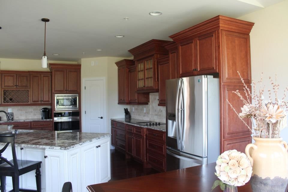 Example of a large classic l-shaped dark wood floor and red floor open concept kitchen design in DC Metro with an undermount sink, raised-panel cabinets, dark wood cabinets, granite countertops, beige backsplash, marble backsplash, stainless steel appliances and an island
