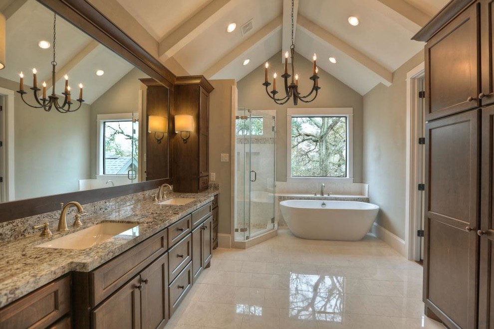 Design ideas for a large arts and crafts master bathroom in Houston with recessed-panel cabinets, dark wood cabinets, a freestanding tub, a corner shower, a two-piece toilet, beige tile, brown tile, white tile, mosaic tile, beige walls, an undermount sink, granite benchtops, marble floors, beige floor and a hinged shower door.