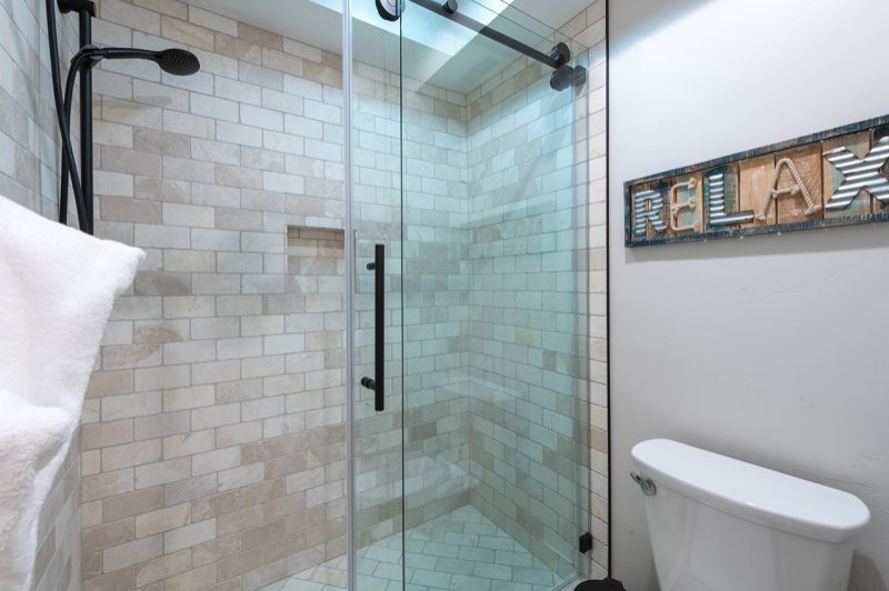 Photo of a small scandinavian shower room bathroom in Salt Lake City with shaker cabinets, grey cabinets, an alcove shower, a one-piece toilet, beige tiles, limestone tiles, beige walls, laminate floors, a submerged sink, engineered stone worktops, multi-coloured floors, a sliding door, white worktops, an enclosed toilet, a single sink and a built in vanity unit.