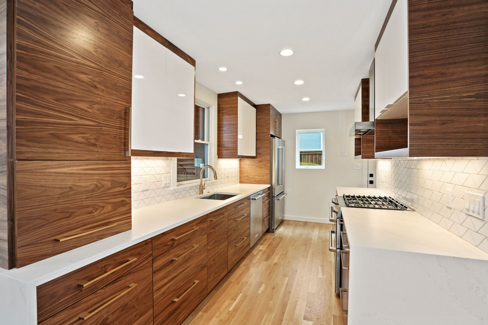 Inspiration for a small modern galley separate kitchen in DC Metro with an undermount sink, flat-panel cabinets, medium wood cabinets, quartz benchtops, white splashback, porcelain splashback, stainless steel appliances, light hardwood floors, no island, brown floor and white benchtop.
