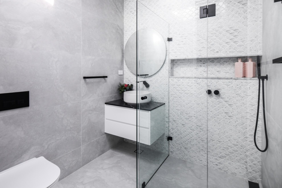 Inspiration for a mid-sized contemporary 3/4 bathroom in Sydney with white cabinets, a freestanding tub, a double shower, a wall-mount toilet, multi-coloured tile, mosaic tile, a vessel sink, marble benchtops, an open shower, black benchtops, a niche, a double vanity and a floating vanity.