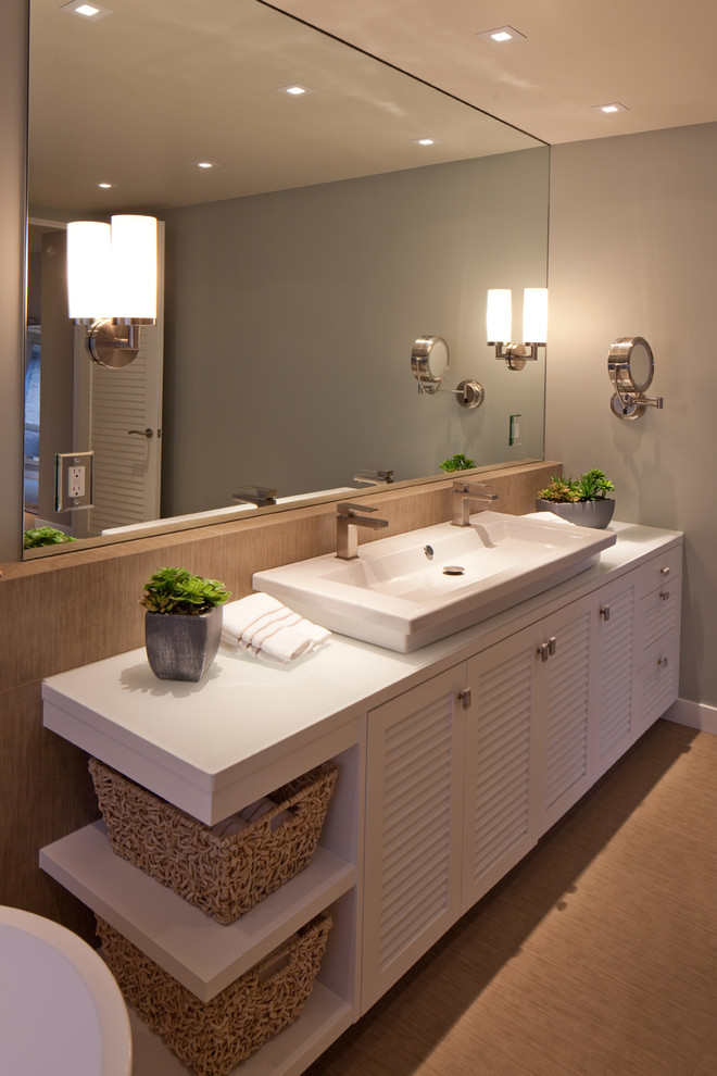 Photo of a mid-sized contemporary master bathroom in San Diego with a trough sink, louvered cabinets, white cabinets, grey walls, ceramic floors, solid surface benchtops and white benchtops.