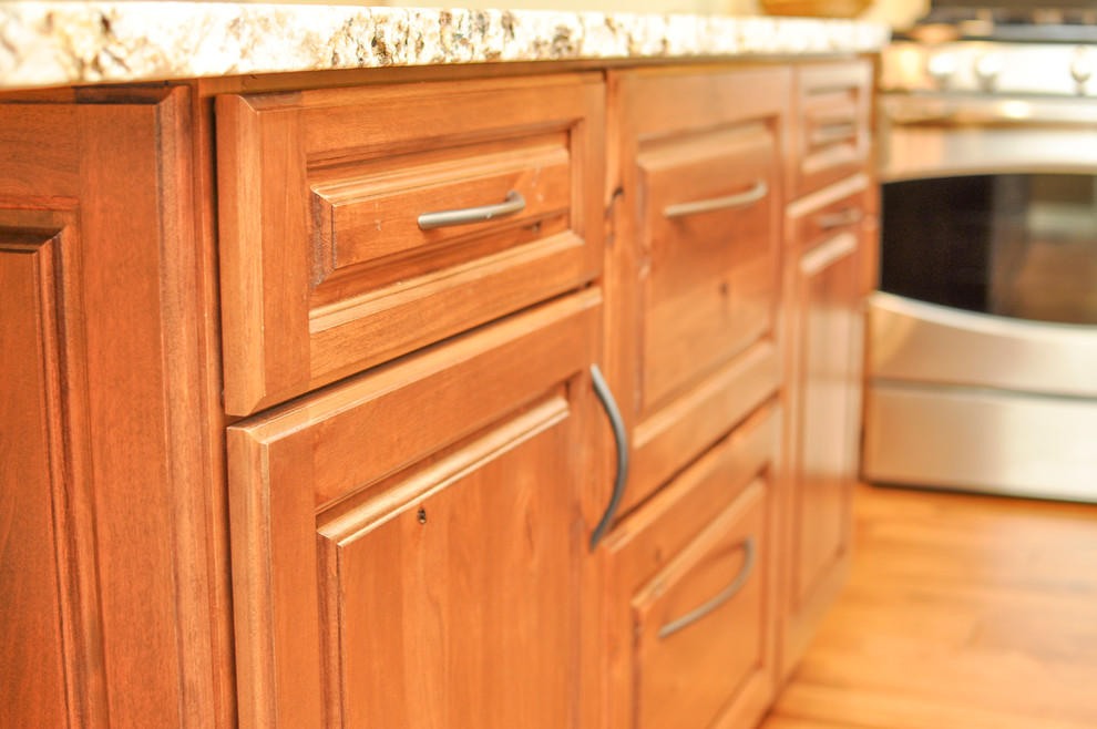 Inspiration for a small transitional u-shaped medium tone wood floor kitchen remodel in Boise with an undermount sink, raised-panel cabinets, medium tone wood cabinets, granite countertops, beige backsplash, porcelain backsplash, stainless steel appliances and an island