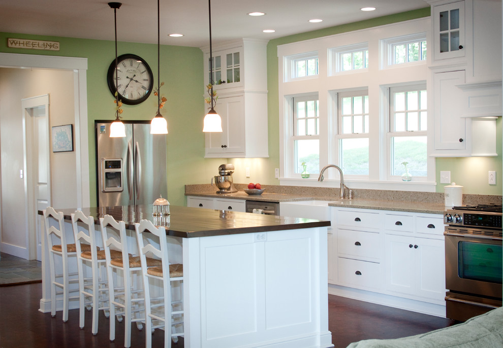 Country kitchen in Other with a farmhouse sink, shaker cabinets, white cabinets and stainless steel appliances.
