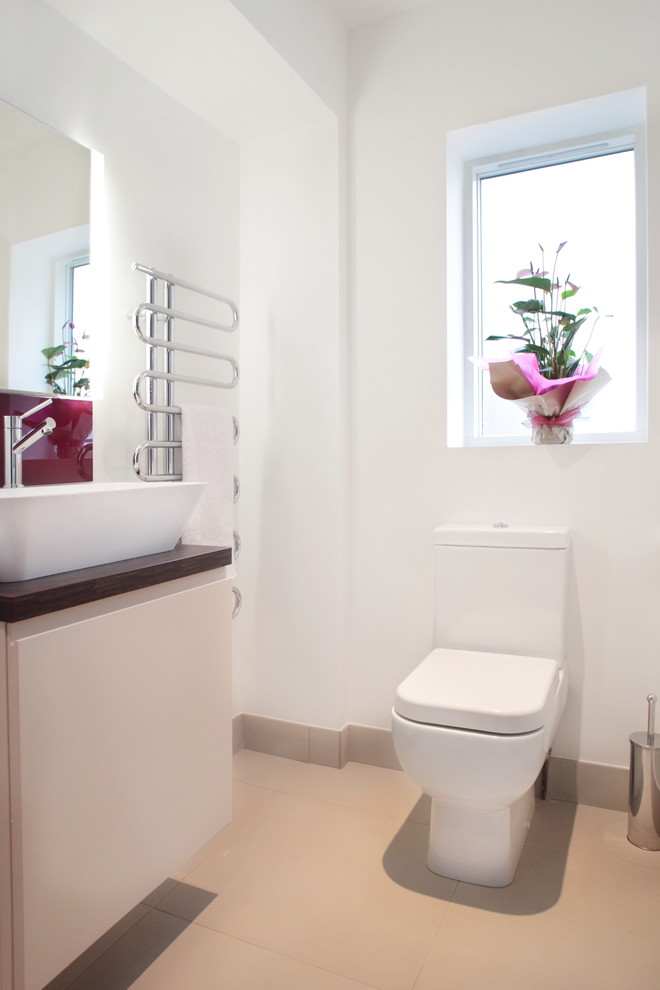 Small contemporary kids bathroom in Buckinghamshire with flat-panel cabinets, white cabinets, a wall-mount toilet, white walls, porcelain floors and wood benchtops.