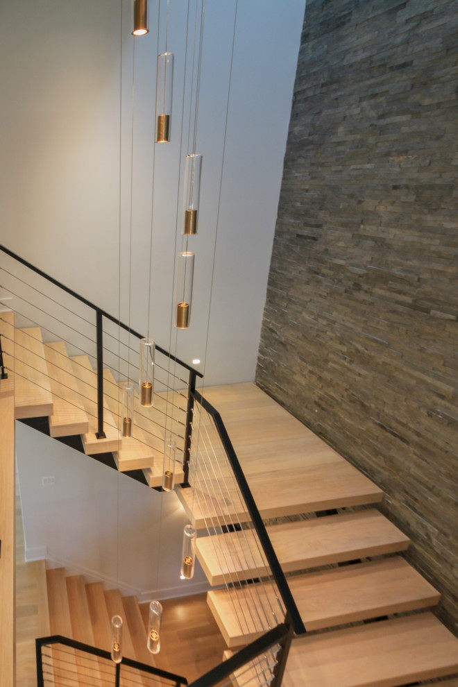 Inspiration pour un grand escalier flottant bohème avec des marches en bois, un garde-corps en métal et un mur en parement de brique.